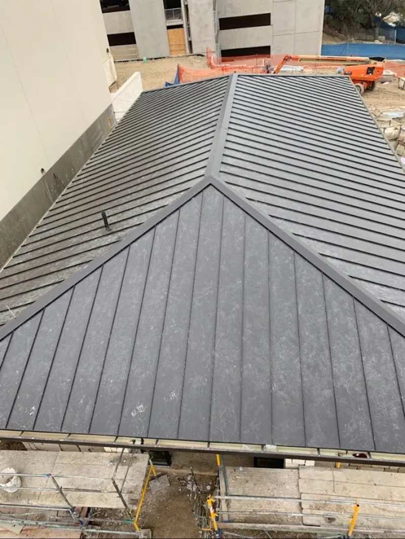 Commercial metal roof construction with crane equipment in Alton
